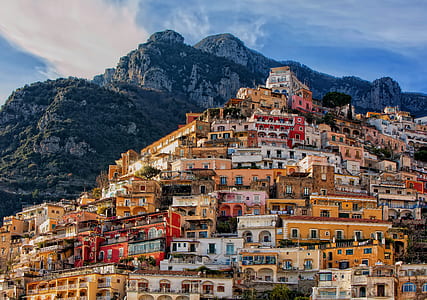 assorted-color concrete houses near mountains at cloudy sky during daytime thumbnail