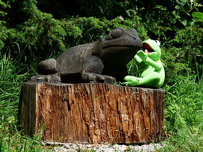 green Kermit the Frog sitting beside gray frog statue thumbnail