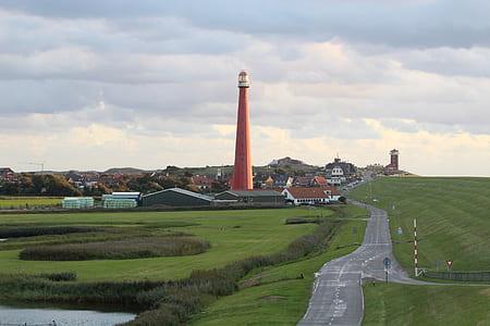 orange lighthouse on green grass field thumbnail