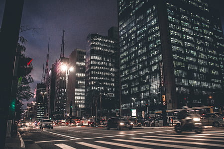 vehicles on road near lighted high-rise buildings during nighttime thumbnail