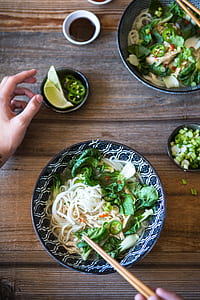 person holding brown chopsticks eating noodle dish thumbnail