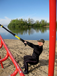 woman pulling yellow and black stick near the body of water at daytime thumbnail