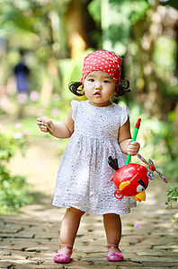girl in white sleeveless dress standing on paver brick during daytime thumbnail