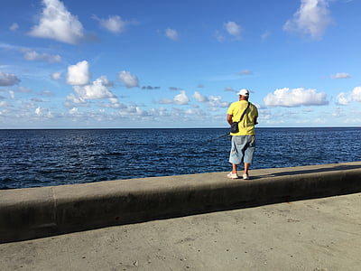 man carrying sling bag standing near body of water thumbnail