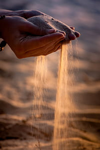 shallow focus photography of person's hands full of sand thumbnail