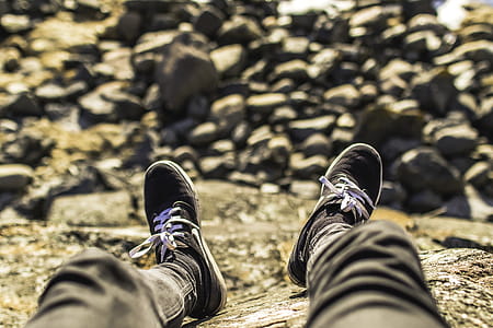 Shallow Focus Photography of Person Wearing Gray Jeans Sitting in Front Rocks thumbnail