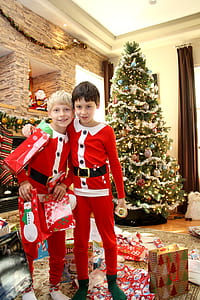two boys standing next to Christmas inside room during daytime thumbnail