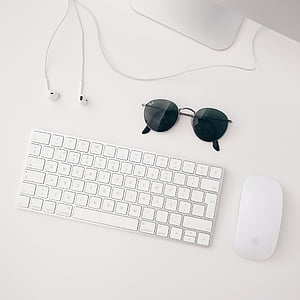 Apple Magic keyboard beside Apple Magic mouse and gray framed Ray-Ban sunglasses thumbnail