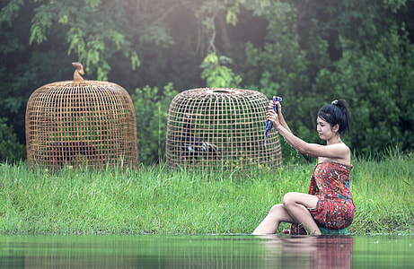 woman in multi-colored strapless dress in body of water near green grass field thumbnail