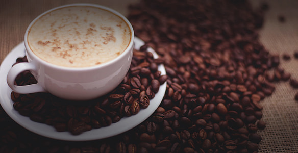 ceramic mug on saucer filled with coffee near coffee beans thumbnail