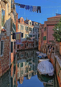 blue and brown boats between houses during daytime thumbnail