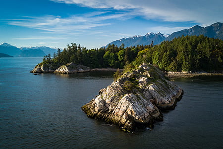 landscape photo of rock isle near tree-covered land aerial photo thumbnail
