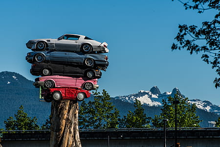 stack of five assorted color cars on tree trunk thumbnail