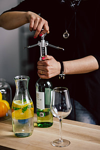Hands opening wine bottle with corkscrew thumbnail