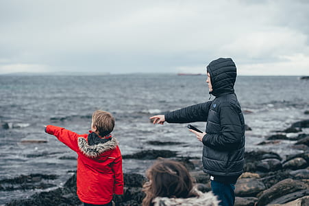 man and boy wearing black and red jackets near body of water thumbnail