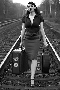 greyscale portrait photograph of woman carrying two luggages thumbnail