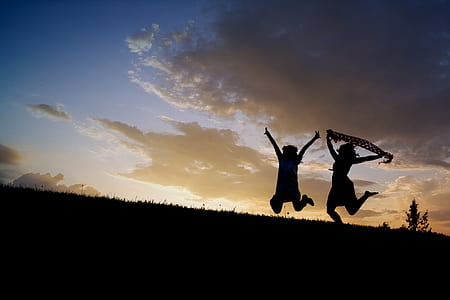silhouette of two people jumping on top of hill thumbnail
