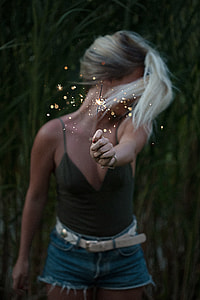 woman in black spaghetti-strap v-neck shirt holding a sparkler during nighttime thumbnail