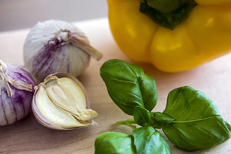 close-up photography of yellow bell pepper, green leaves and onions on brown wooden surface thumbnail