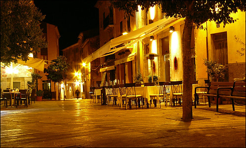 empty tables and chairs near tree during night time thumbnail