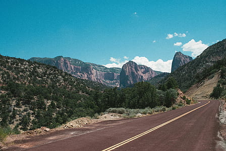 mountain ranges near road under cloudy sky thumbnail