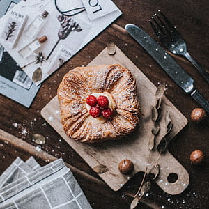 bread with strawberries beside cutlery on top of table thumbnail
