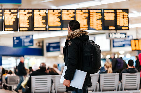 man wearing black and brown parka jacket standing while looking at display monitor thumbnail