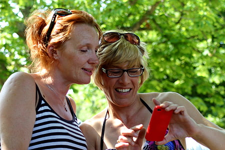 two woman both watching at phone's screen thumbnail