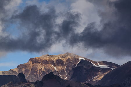 brown rock mountain under dark clouds thumbnail