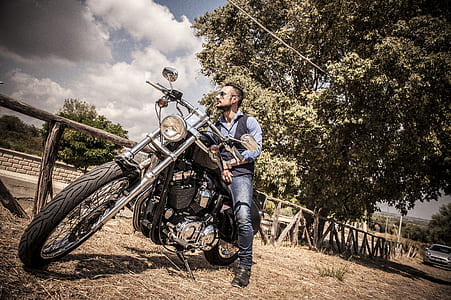 man riding cruiser motorcycle near tree thumbnail
