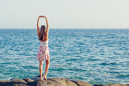 woman wearing white and pink mini dress near the ocean flexing thumbnail