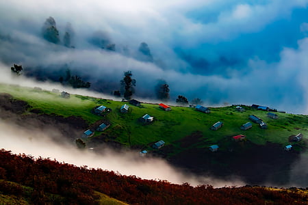 assorted-color houses on green field surrounded with smokes thumbnail