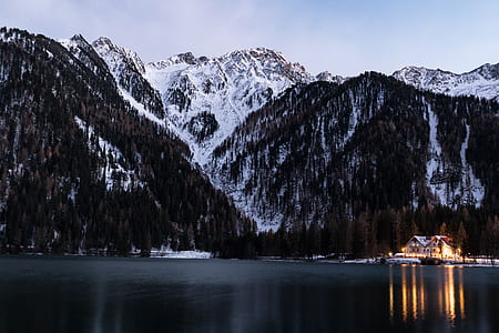 lighted brown house in between mountain and body of water during golden hour thumbnail
