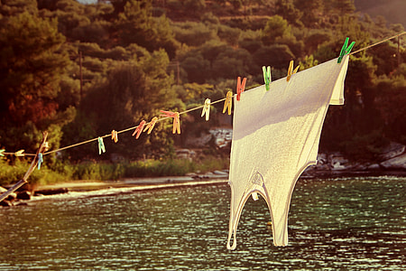 photography of white tank top hang on clothesline above the body of water thumbnail