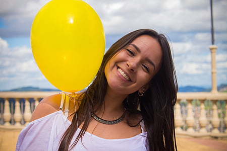woman in white top holding yellow balloon thumbnail