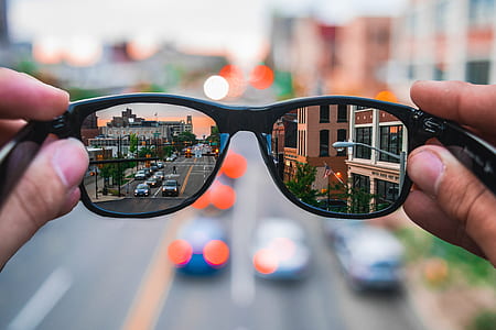 selective focus photography of person holding black frame sunglasses thumbnail