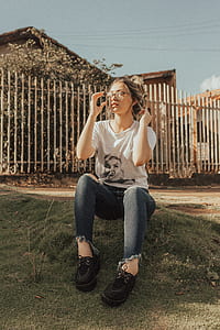 woman sitting on green grass in front of house and fence thumbnail