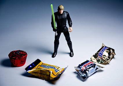 Luke Skywalker action figure behind four assorted-brand chocolate packs thumbnail