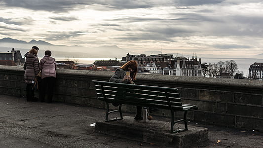 Woman Taking Photo While Sitting on the Bench Behind the Building Scenery thumbnail