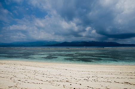 white sand near seashore during cloudy day thumbnail