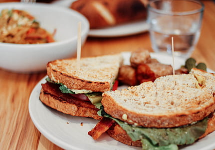 two sliced of breads with bacon on round white plates thumbnail