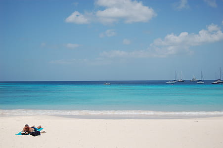 man lying on sand near body of water thumbnail