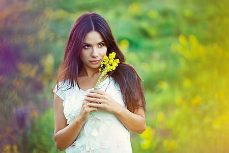 woman wearing black top holding yellow flowers thumbnail