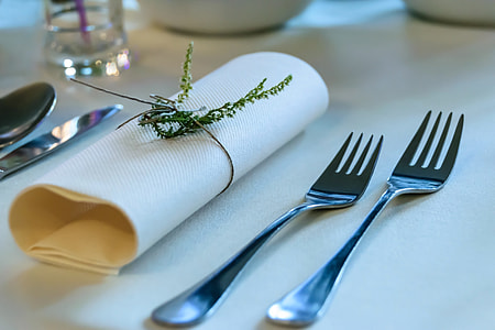 two gray stainless steel forks beside white table napkin thumbnail