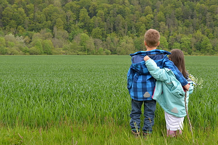 boy and girl standing on green grass field thumbnail