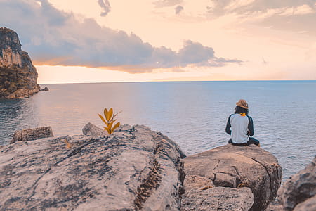 Person Sitting on Cliff Near Body of Water thumbnail