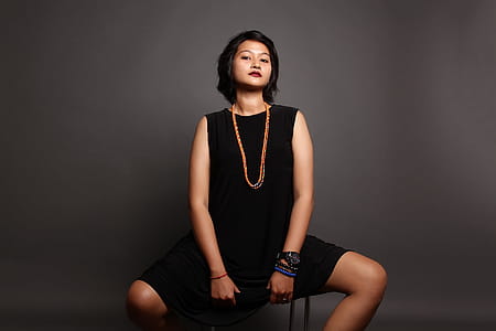 Woman Siting on a Stool in Front of a Gray Background thumbnail