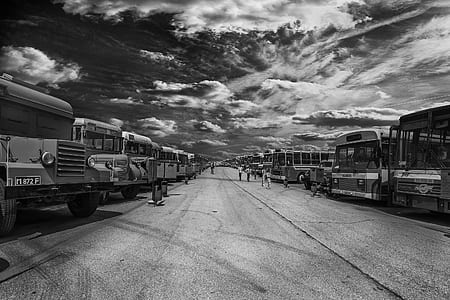 grayscale photo of person walking on street beside bus station thumbnail