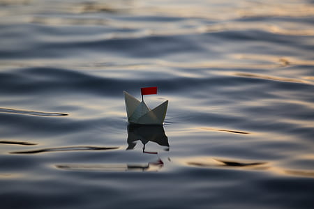 white paper boat on body of water at daytime thumbnail