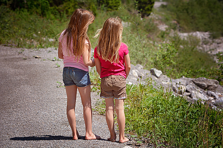 two girls standing in front of green grasses during daytime thumbnail